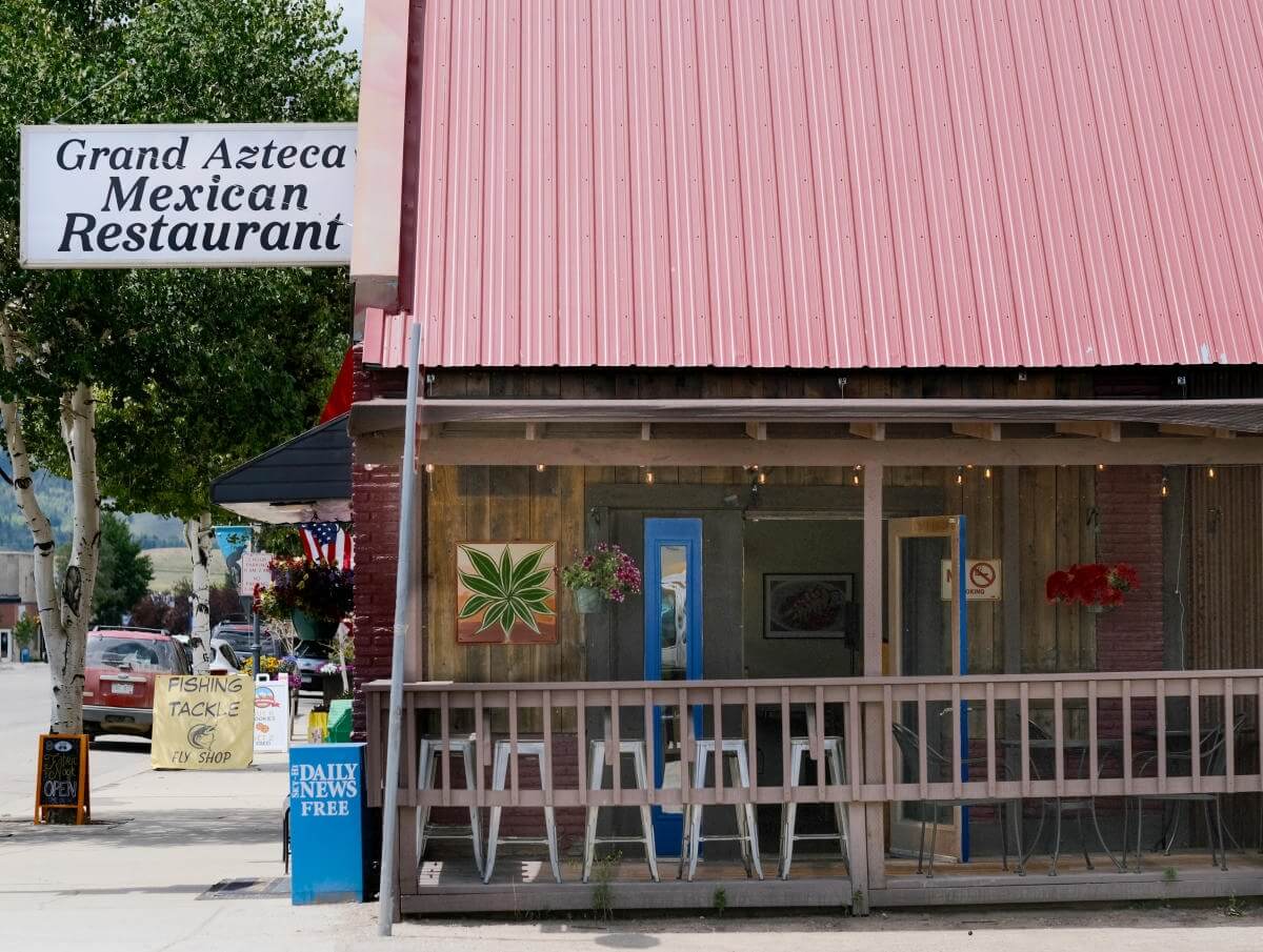 A vibrant pink-roofed restaurant with a wooden deck and a sign reading 'Grand Azteca Mexican Restaurant' in Grand County Colorado.
