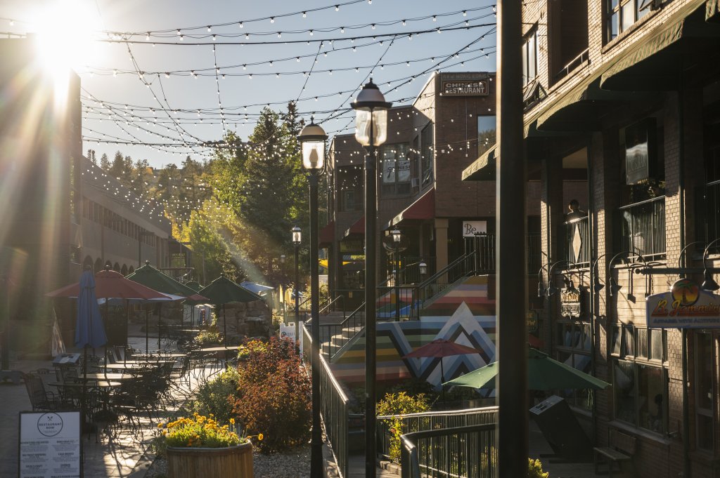 Sunlit walkway with string lights and outdoor seating at Cooper Creek Square.