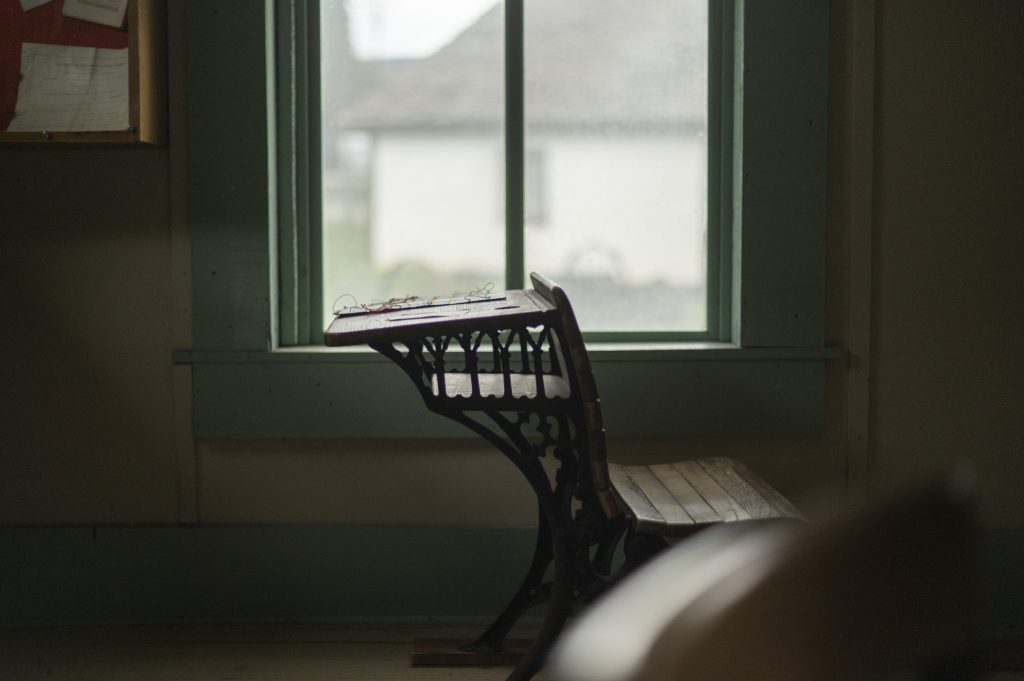 Antique wooden school desk by a window at Pioneer Village Museum.