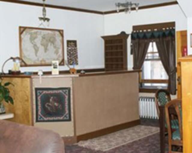 A cozy room with a wooden desk, map, and window with curtains in Grand County Colorado.