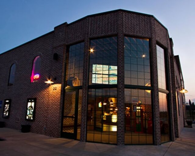A brick building with large windows and neon signs illuminated at dusk in Grand County Colorado.