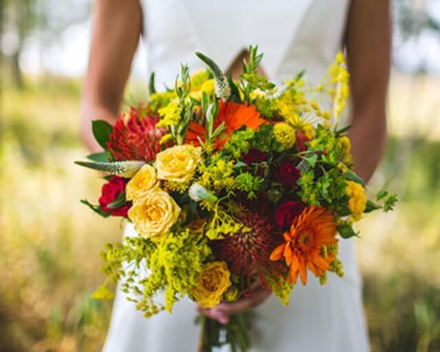 A vibrant bouquet of colorful wildflowers held by a person in a white dress in Grand County Colorado.