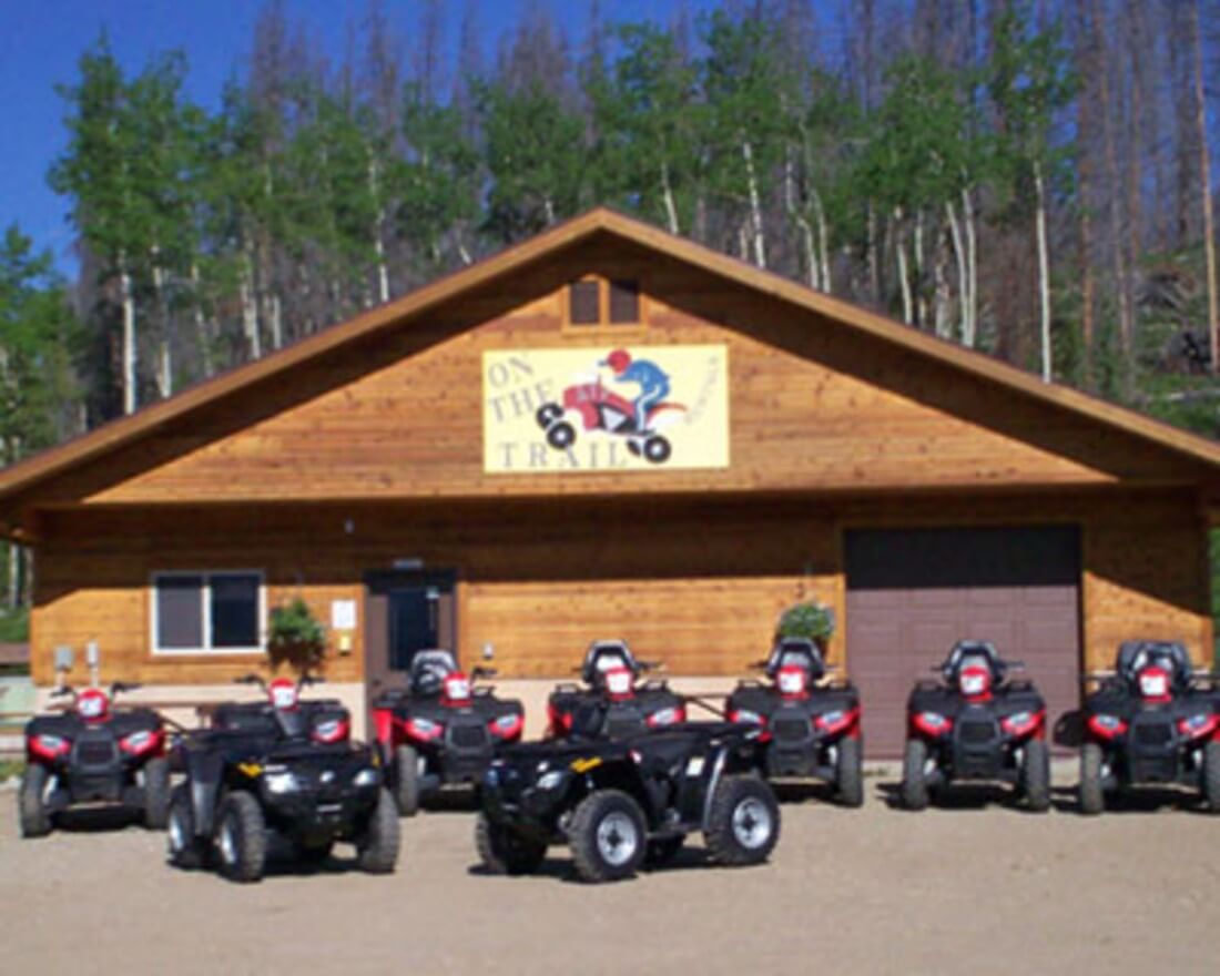 A wooden building with 'On the Trail' sign and ATVs parked in front in Grand County Colorado.