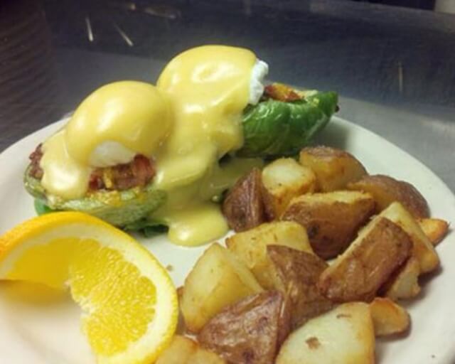 A plate with eggs benedict on a green pepper, roasted potatoes, and a lemon wedge in Grand County Colorado.