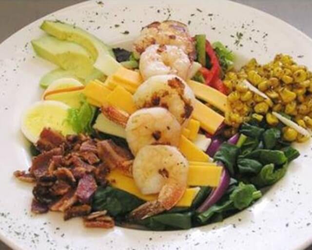Colorful salad with grilled shrimp, avocado, corn, bacon, cheese, and hard-boiled egg in Grand County Colorado.