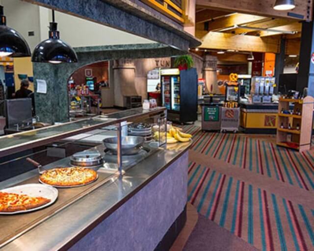 A bustling cafeteria with a variety of food options, including pizzas and salads in Grand County Colorado.