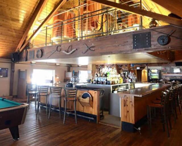 A rustic bar with wooden beams, a pool table, and a variety of seating options in Grand County Colorado.