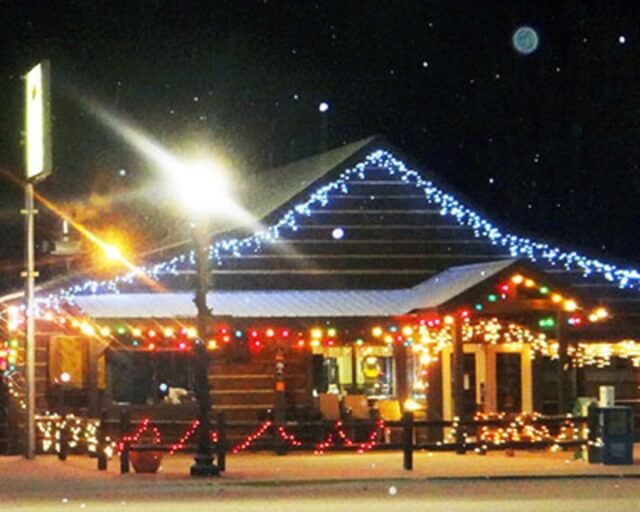 A rustic wooden building is festively decorated with colorful Christmas lights at night in Grand County Colorado.