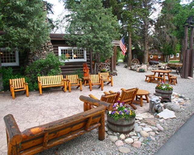 Rustic outdoor seating area with wooden furniture and potted plants in Grand County Colorado.