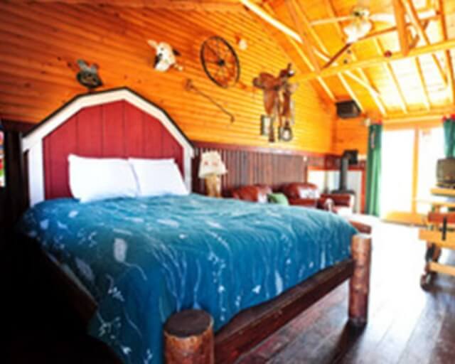 Rustic bedroom with wooden beams, red and white barn-style headboard, and blue floral bedding in Grand County Colorado.