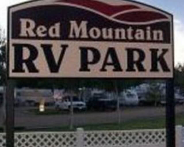 A sign for Red Mountain RV Park with a mountain design and white picket fence in Grand County Colorado.