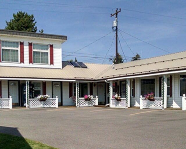 A quaint motel with white and red exterior, flower boxes, and a parking lot in Grand County Colorado.