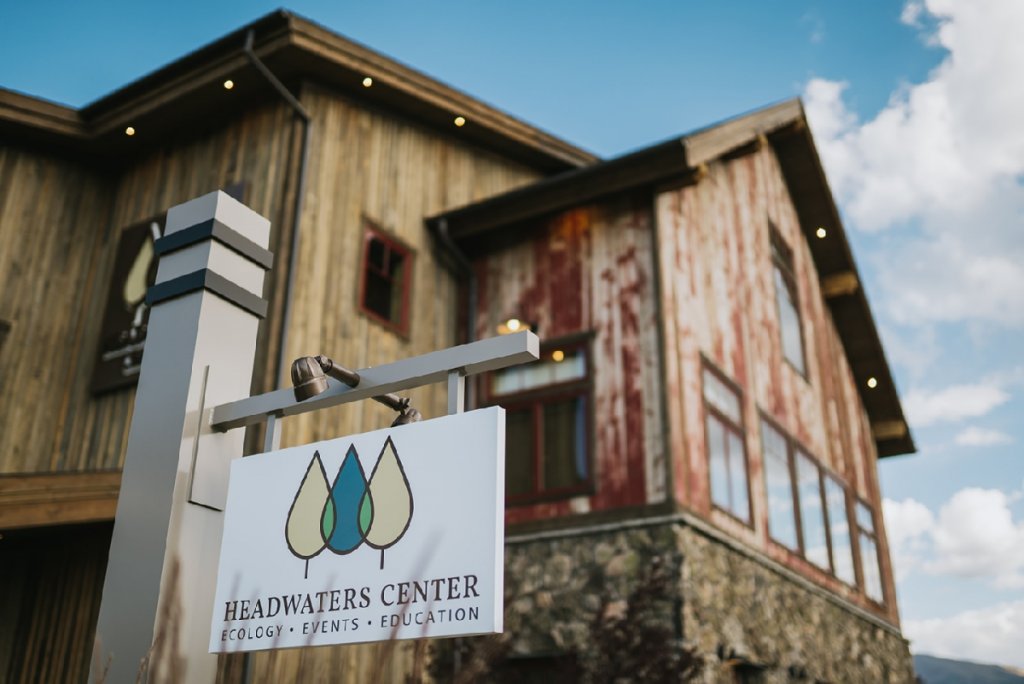 A rustic wooden building with a sign for the Headwaters Center for Ecology, Events, and Education in Grand County Colorado.