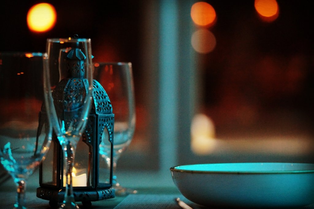 A decorative lantern with a lit candle inside is placed on a table with wine glasses and a bowl in Grand County Colorado.