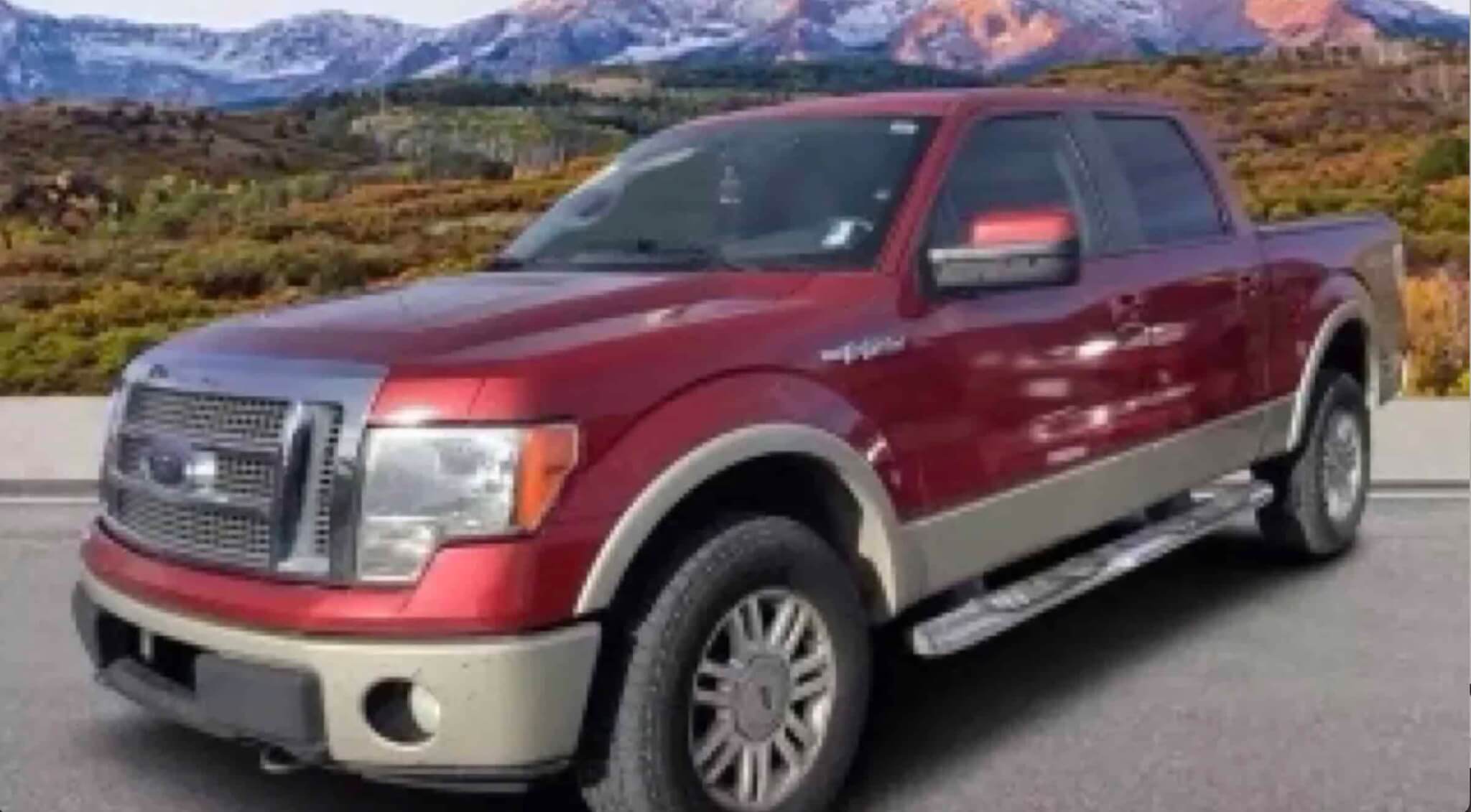 A maroon Ford F-150 pickup truck parked on a paved road with mountains in the background in Grand County Colorado.