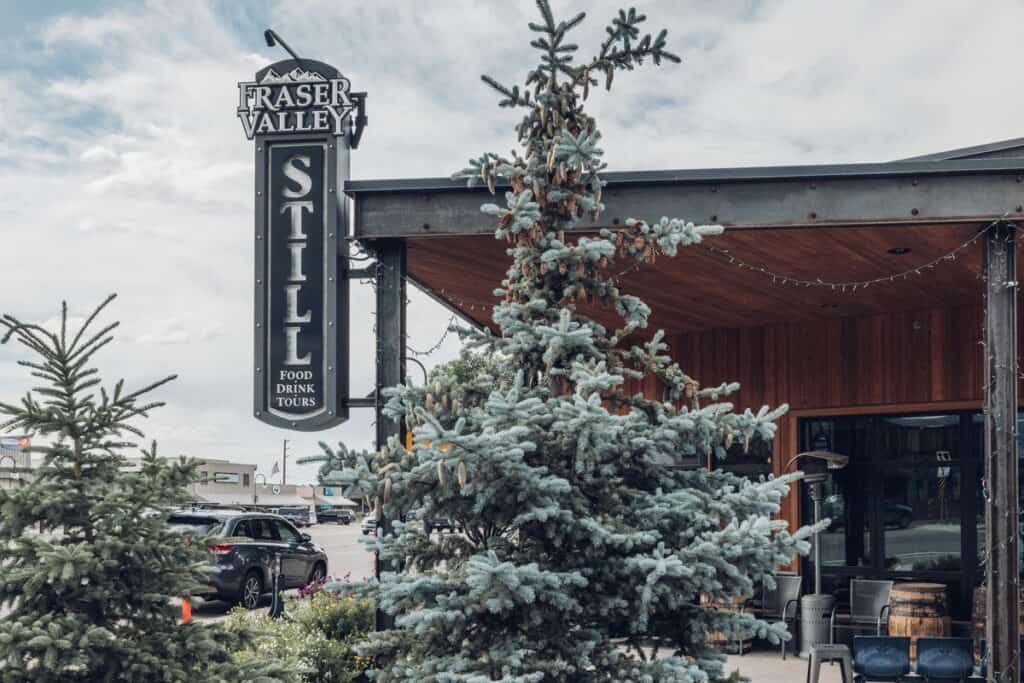 A sign for a restaurant with a tree in front of it.