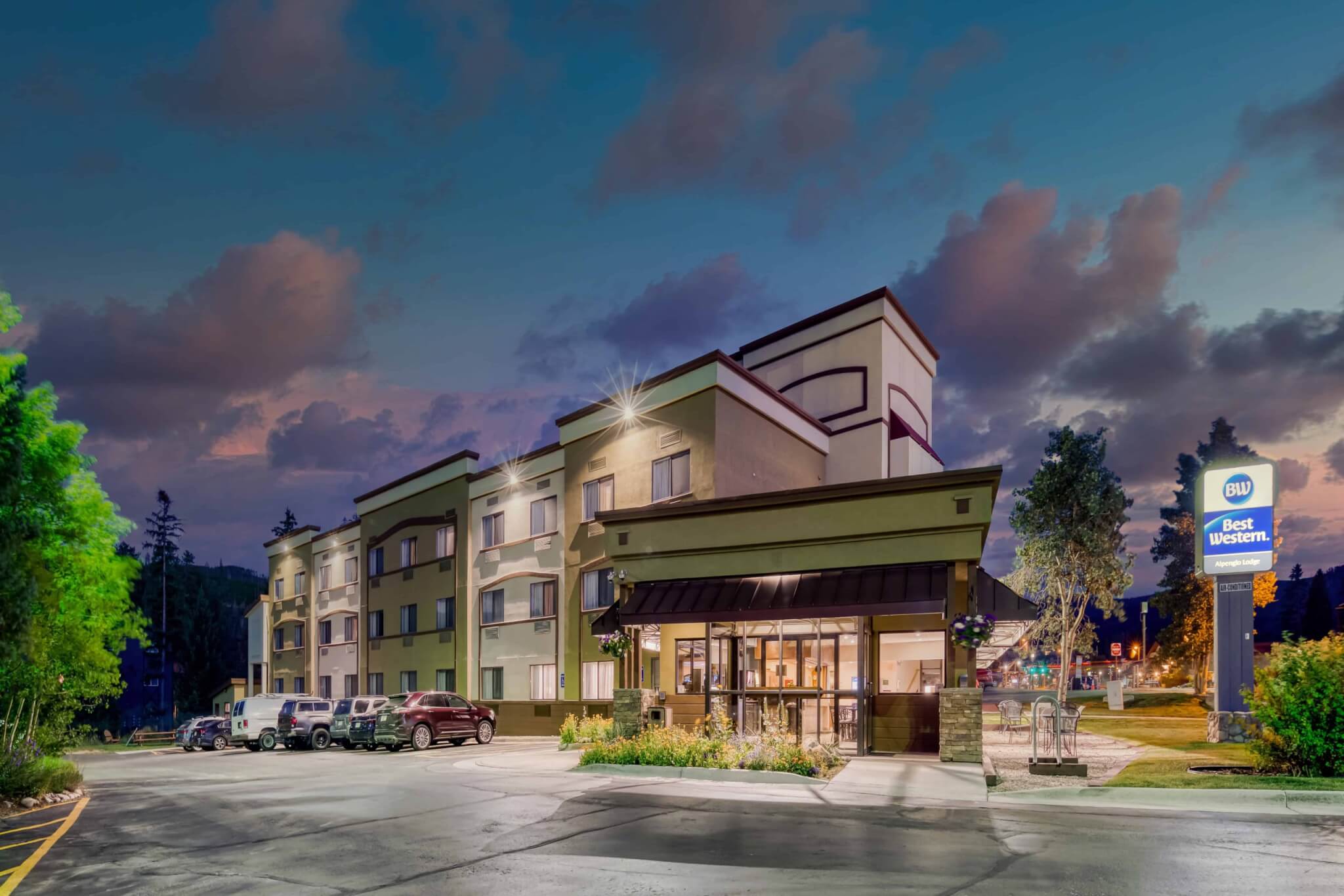 A modern hotel with a green roof and beige walls, illuminated at night with a sign reading 'Best Western' in Grand County Colorado.