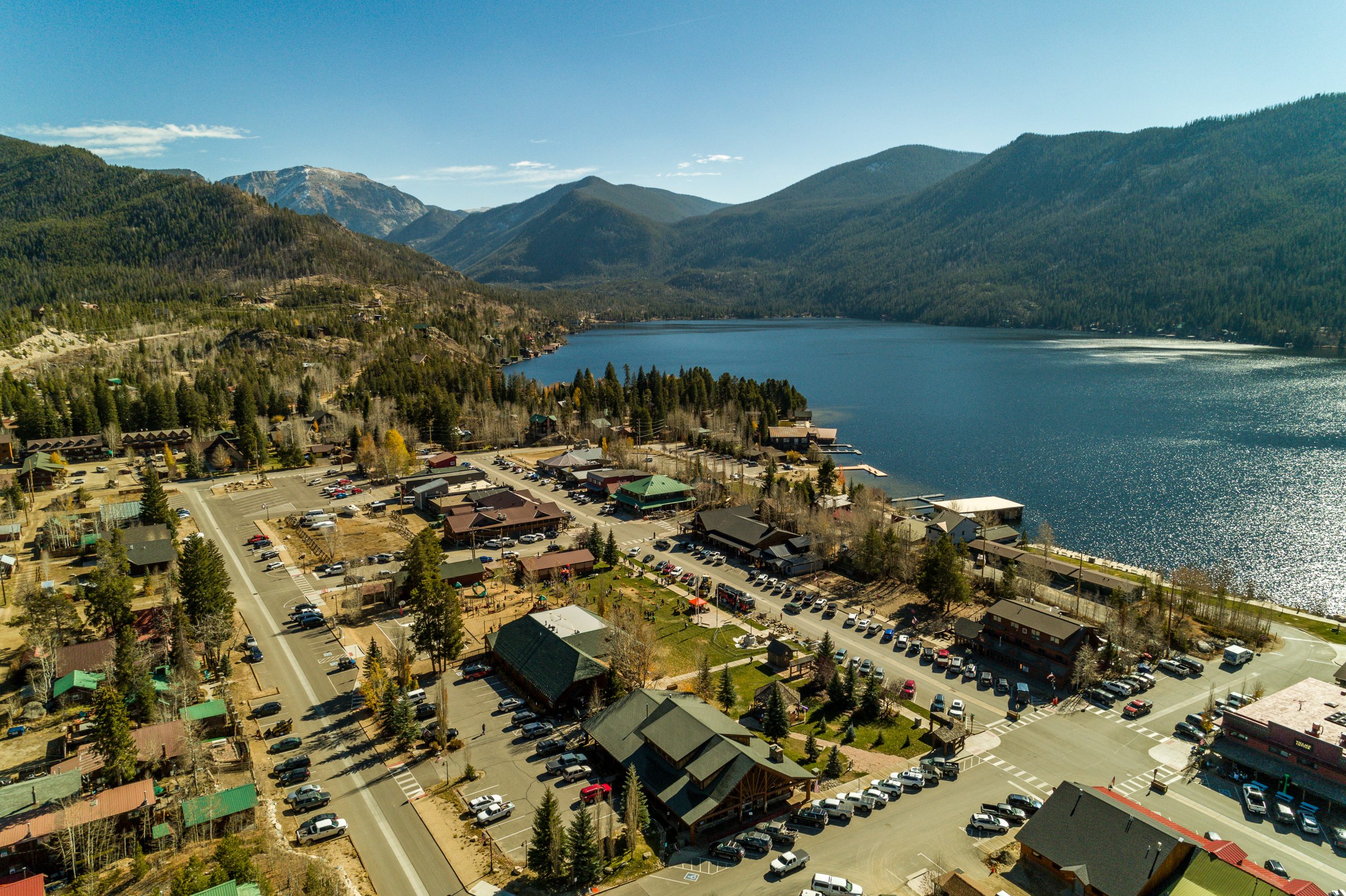 Aerial view of downtown Grand Lake with mountains and water in the background.