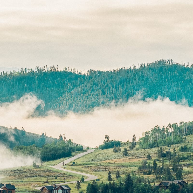 A view of a mountain with fog and houses in the distance.