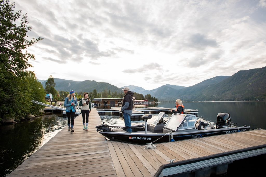 People walking on a wooden dock with boats and mountains in the background in Grand County Colorado.