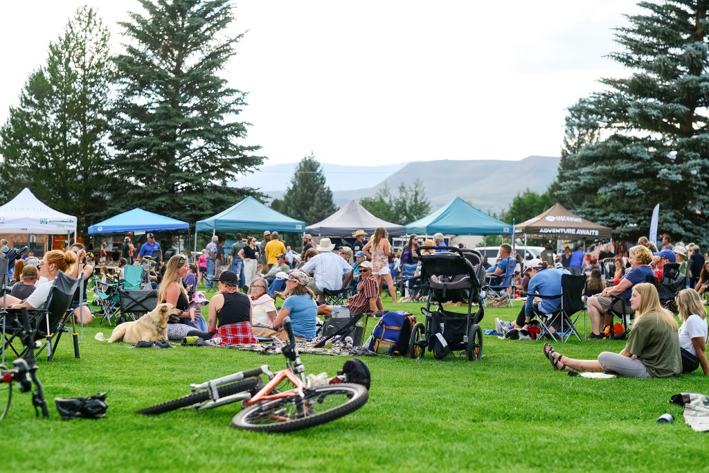 People walking and browsing vendor tents at an outdoor Colorado farmers market in Grand County.