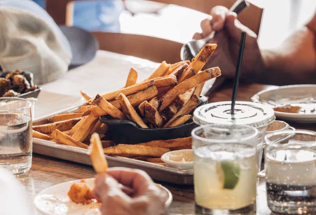 A group of people eating french fries at a table.