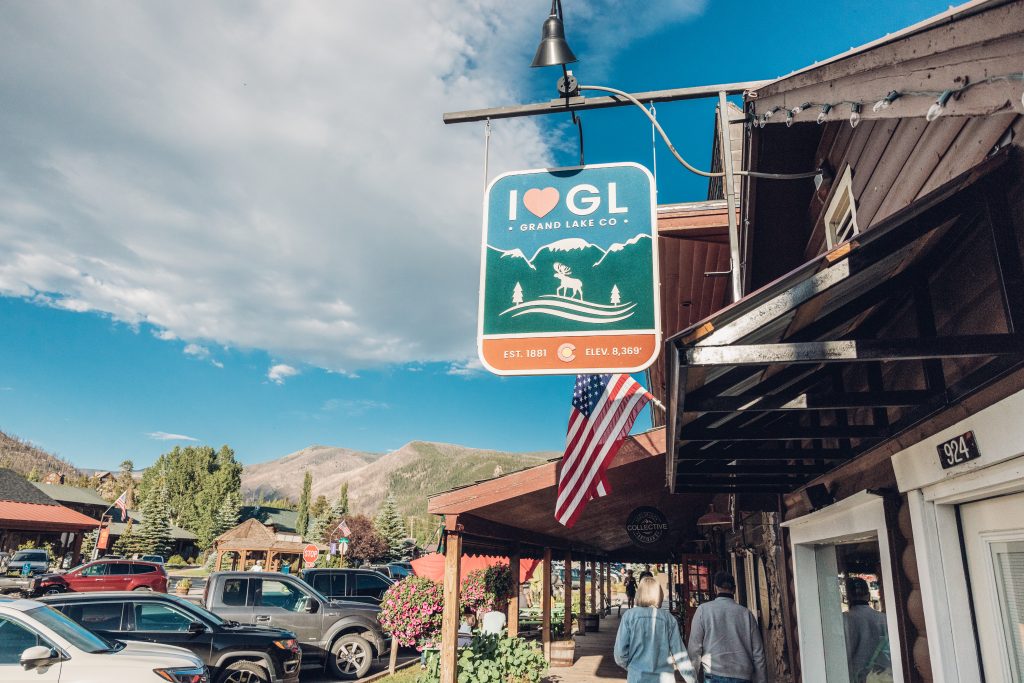 I Love Grand Lake sign above a wooden boardwalk with people walking below.