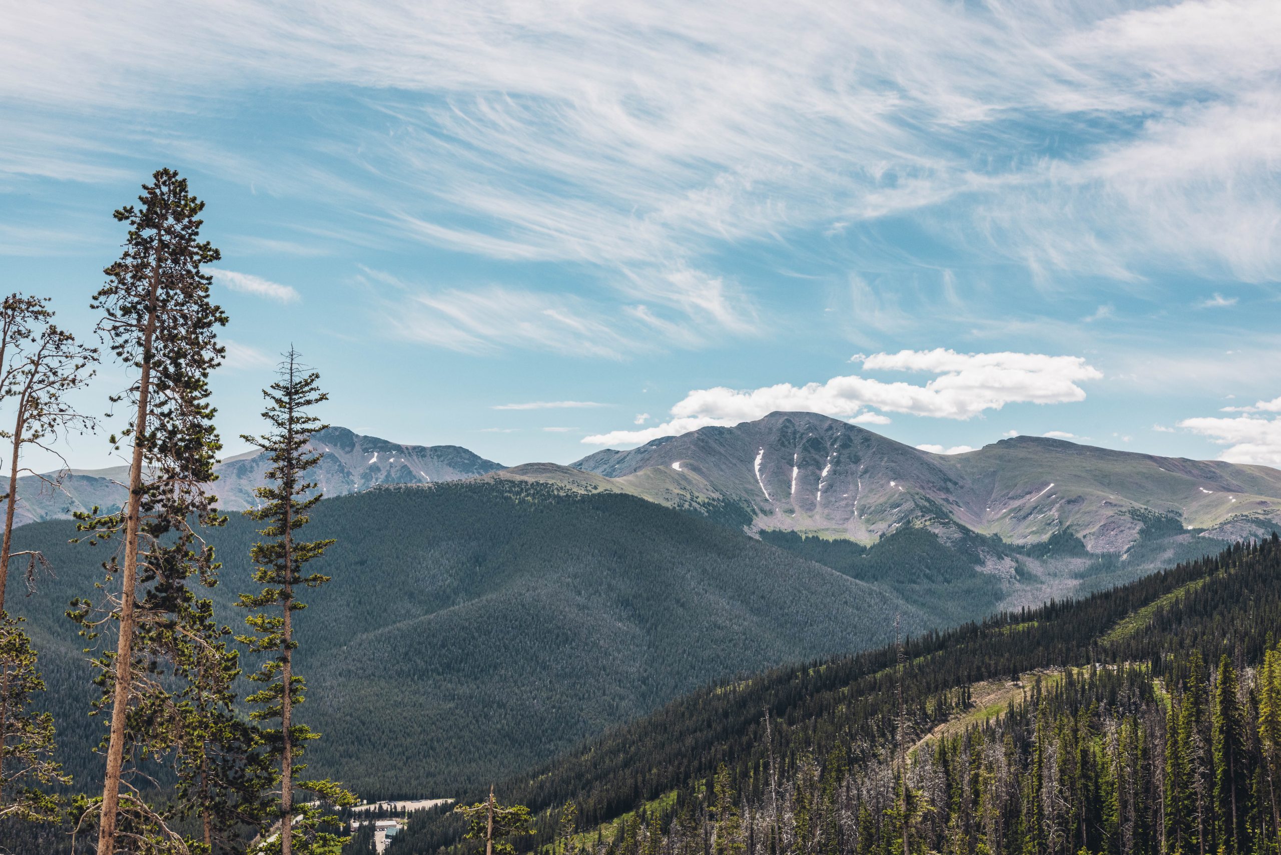A vast mountain range with snow-capped peaks and dense evergreen forests stretches into the distance in Grand County Colorado.