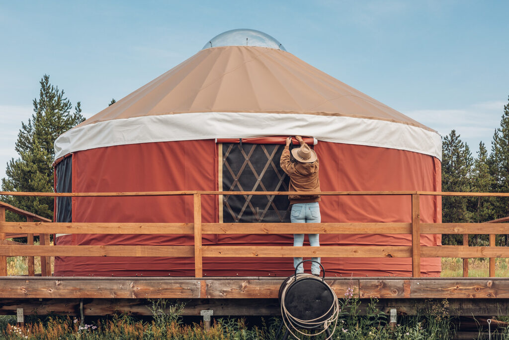 A person standing on a wooden deck next to a yurt.