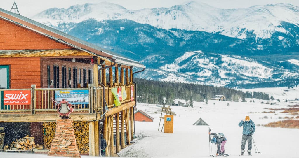 A group of people standing in front of a ski lodge.