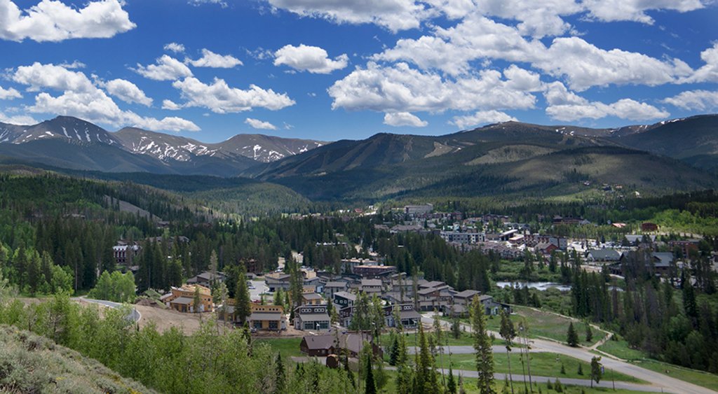 A picturesque mountain town nestled among evergreen forests with snow-capped peaks in the distance in Grand County Colorado.