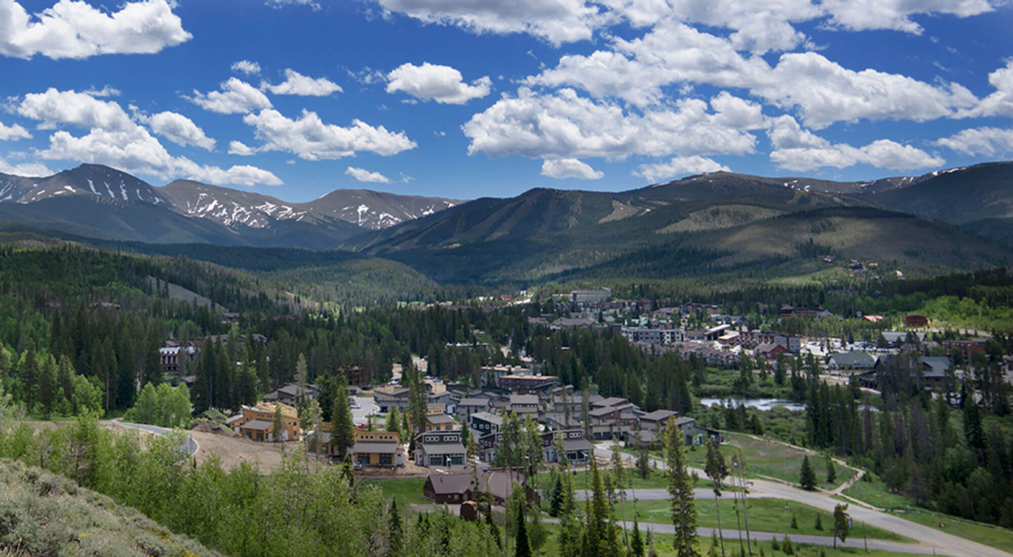 A picturesque mountain town nestled among evergreen forests with snow-capped peaks in the distance in Grand County Colorado.