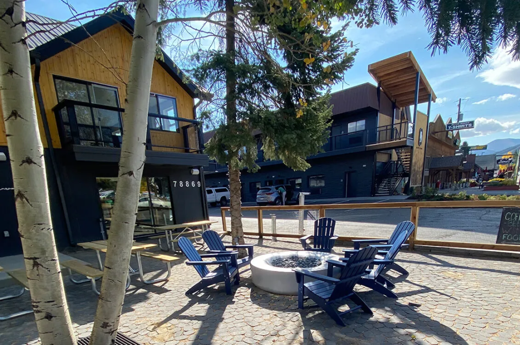 Outdoor seating area with blue Adirondack chairs around a fire pit in a paved courtyard in Grand County Colorado.