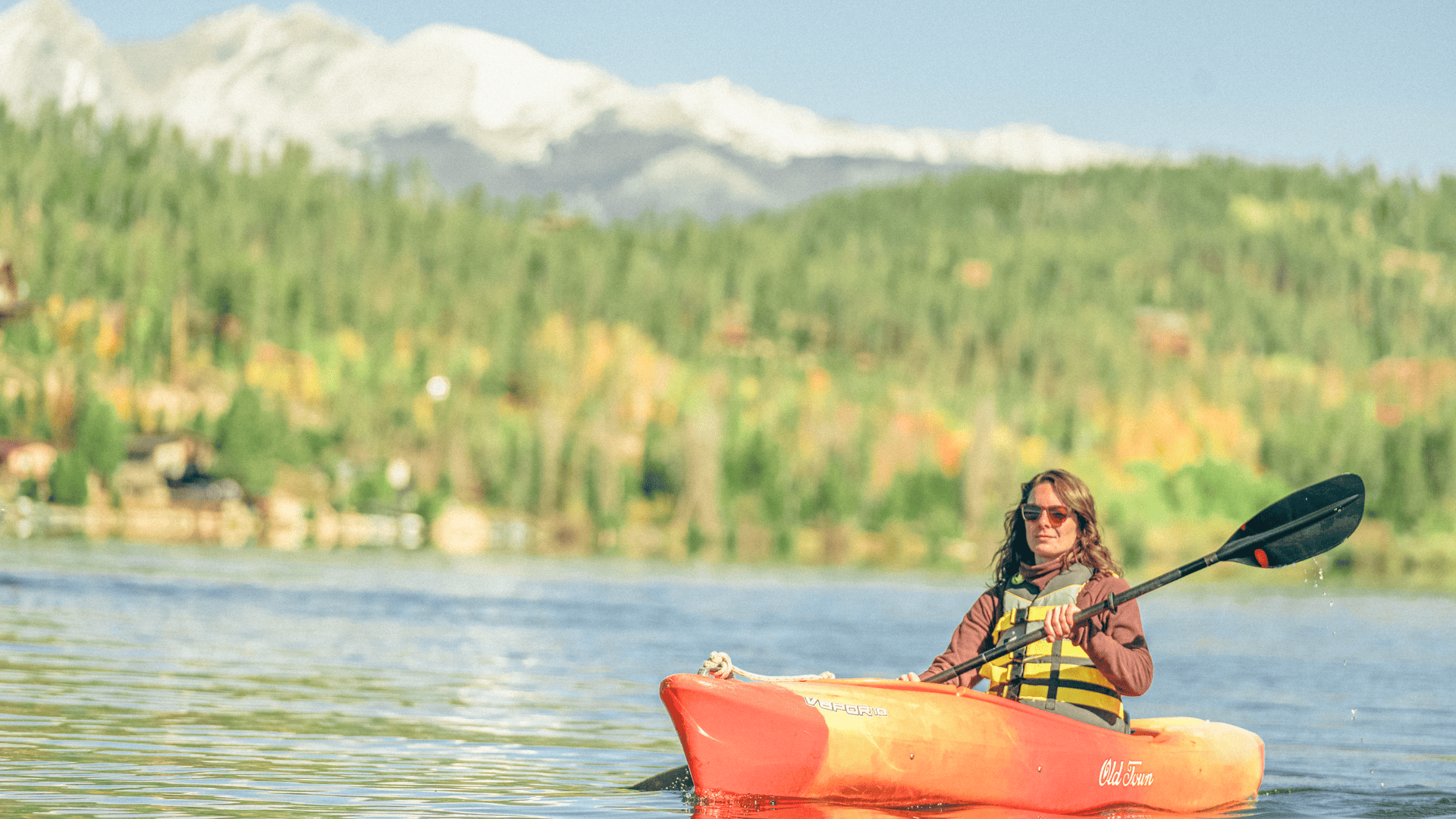 Person kayaking on Grand Lake, Colorado, with scenic mountain views in the background.