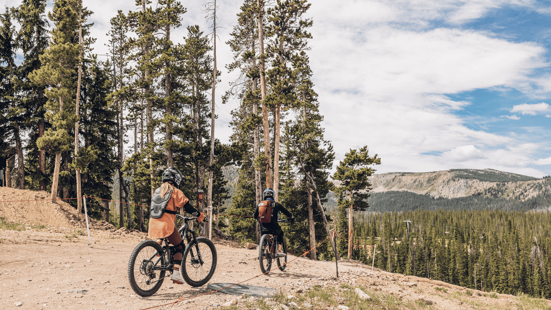 Two mountain bikers riding down a trail in the mountains.